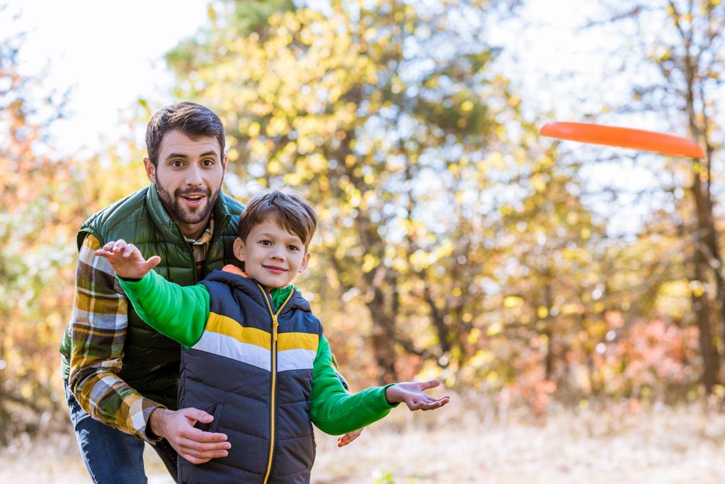 Uśmiechnięty ojciec i syn, grając z frisbee - Zdjęcie, obraz