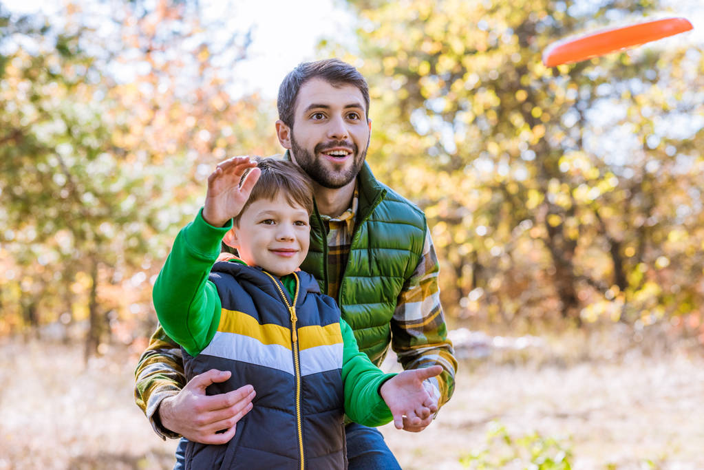 Mosolyogva, apa és fia, játék frisbee - Fotó, kép
