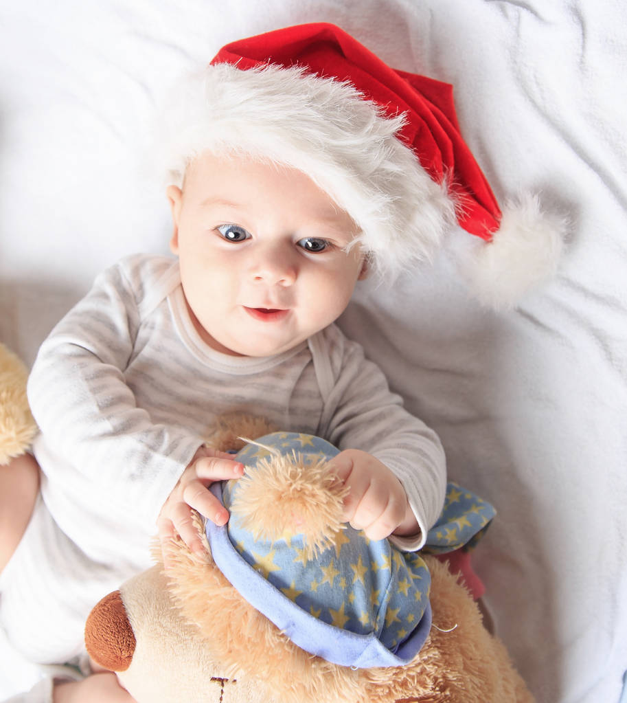 niedliches Baby im Kostüm des Weihnachtsmannes mit einem Spielzeug. - Foto, Bild