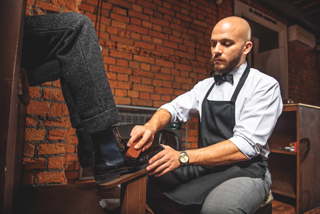 elegante man schoonmaken van schoeisel voor een client - Foto, afbeelding