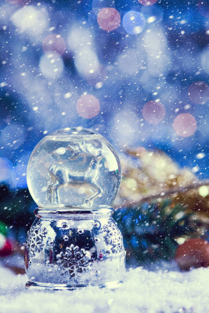 Snow Falling On Christmas Reindeer Snow Globe With Decor On Snow. Vintage Filter Applied. - Photo, Image