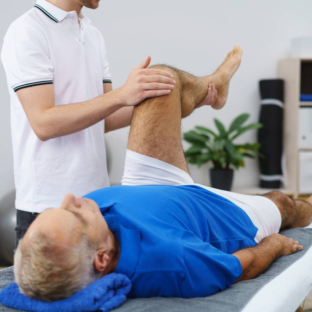 fisioterapeuta manipula anciano mans pierna
 - Foto, Imagen