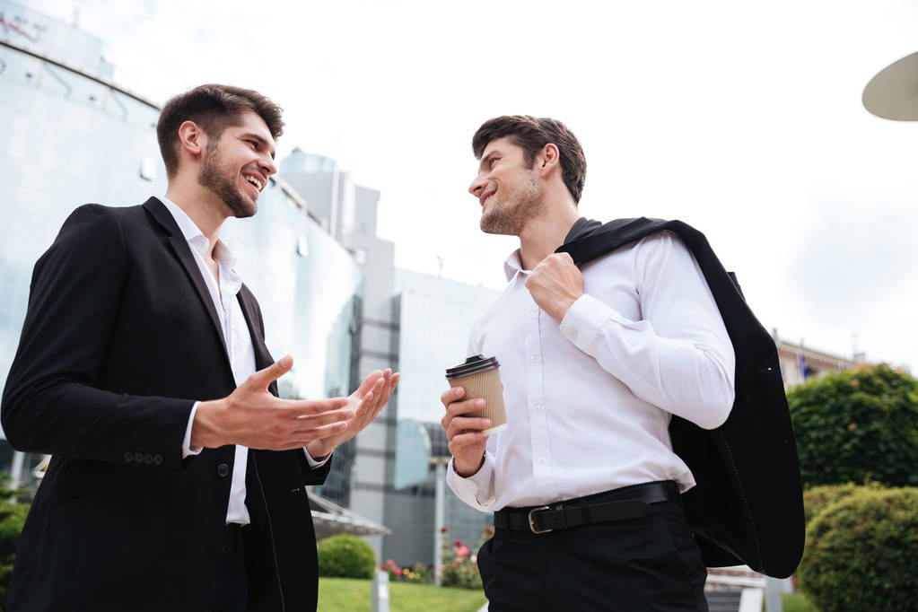 Dos jóvenes empresarios alegres tomando café al aire libre
 - Foto, Imagen
