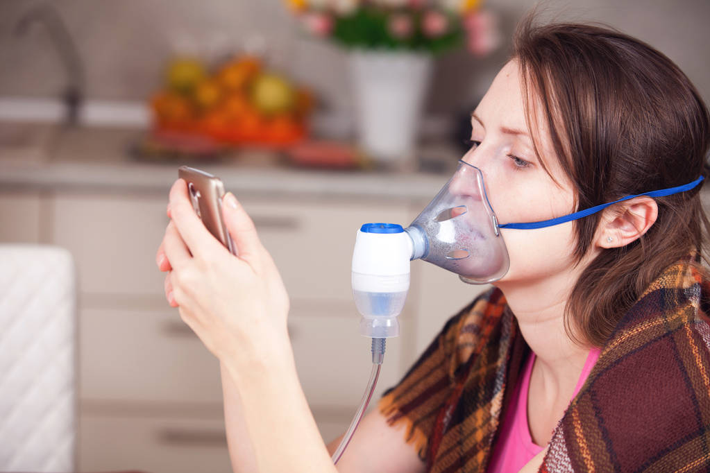 Mujer joven haciendo inhalación con un nebulizador en casa
 - Foto, Imagen