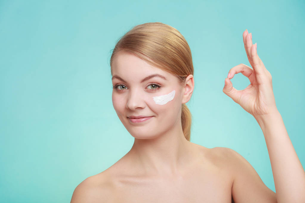 mujer aplicando crema en su cara de piel. - Foto, Imagen