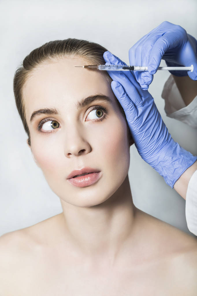 Médico esteticista hace inyecciones de belleza facial a paciente femenino
 - Foto, Imagen