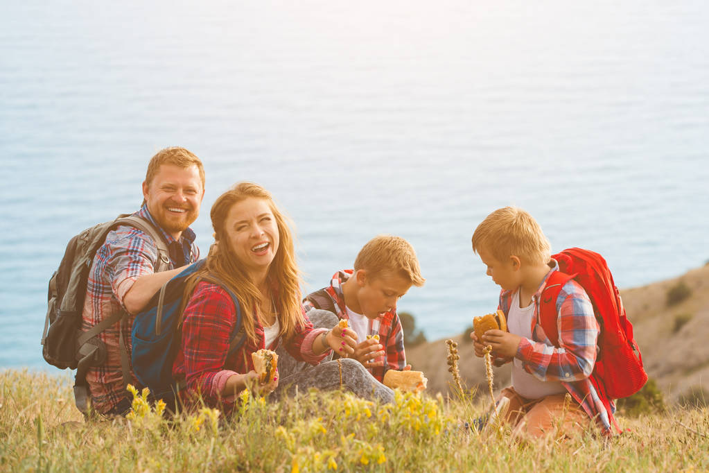 Familia de cuatro personas comiendo comida rápida en las montañas
 - Foto, imagen