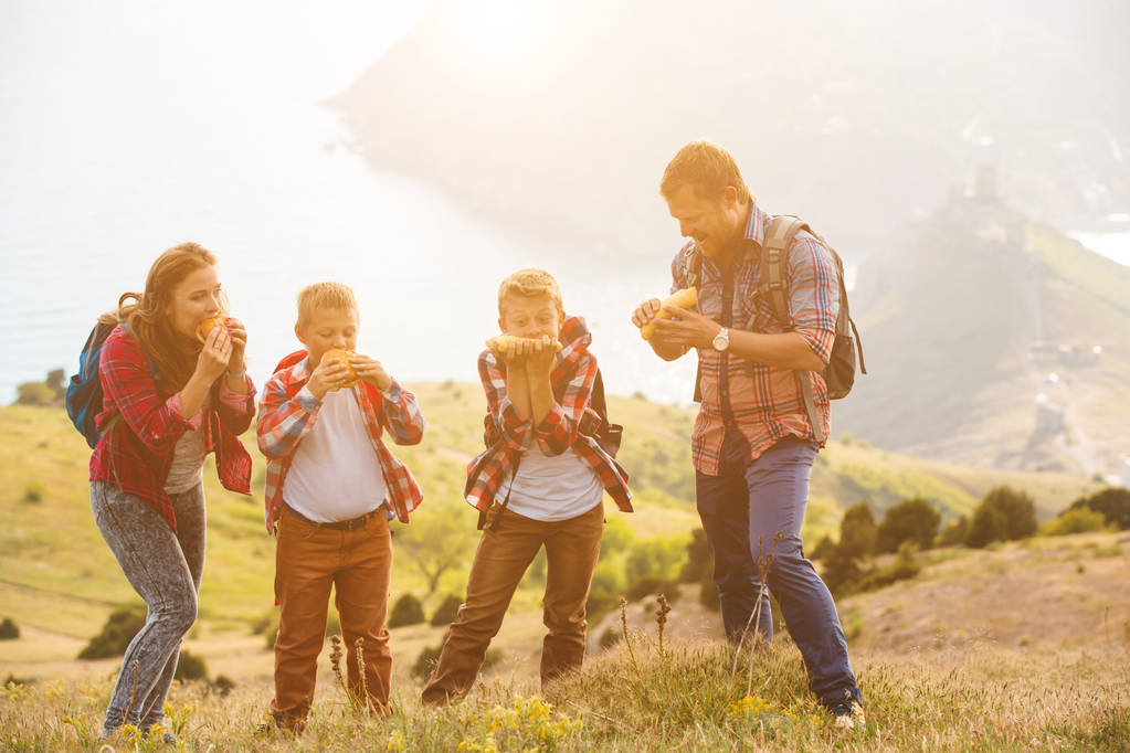 Familia de cuatro personas comiendo comida rápida en las montañas
 - Foto, imagen