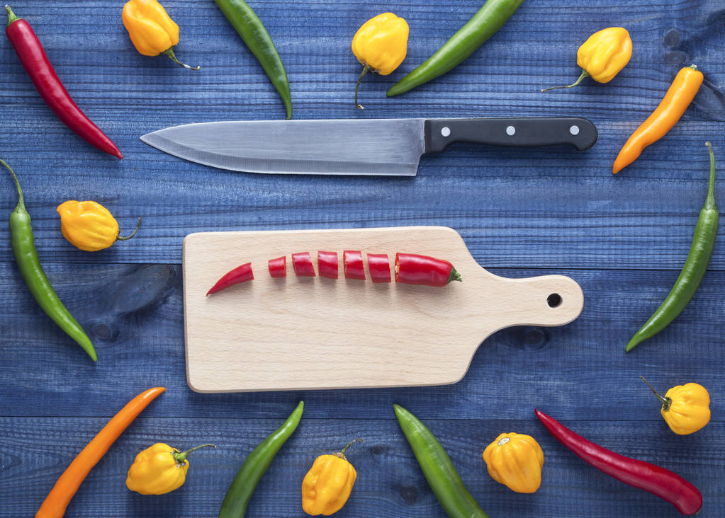 chopped cayenne chilli pepper on cutting board with other peppers all around - Photo, Image