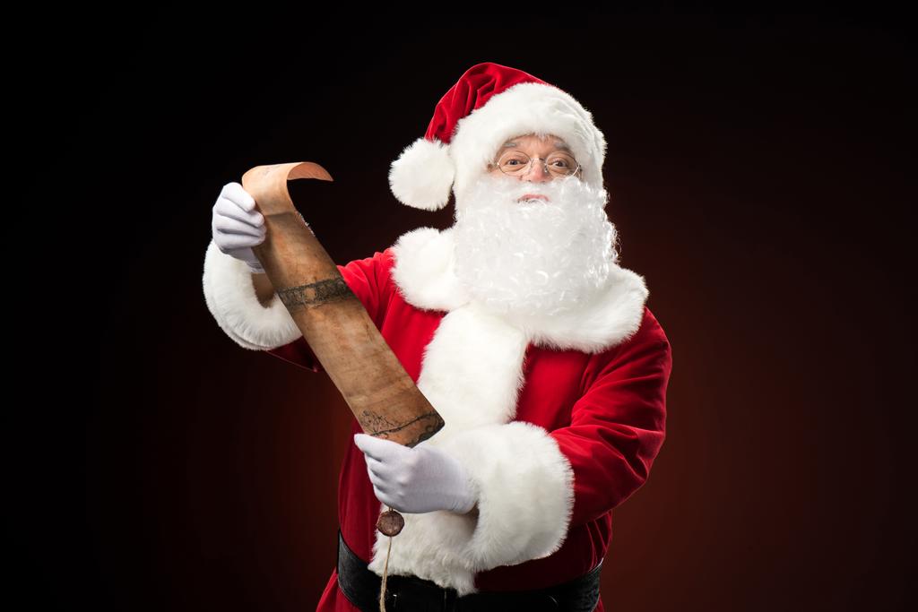 Papai Noel de pé com lista de desejos
 - Foto, Imagem