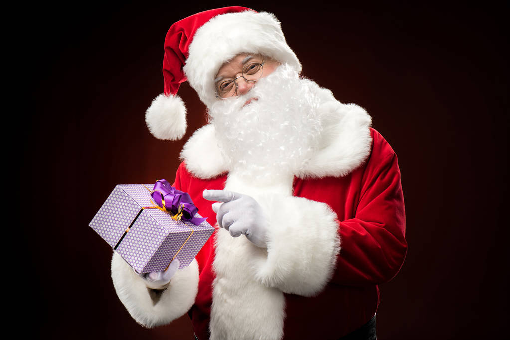 Joulupukki osoittaa lahjapakkaukseen
 - Valokuva, kuva