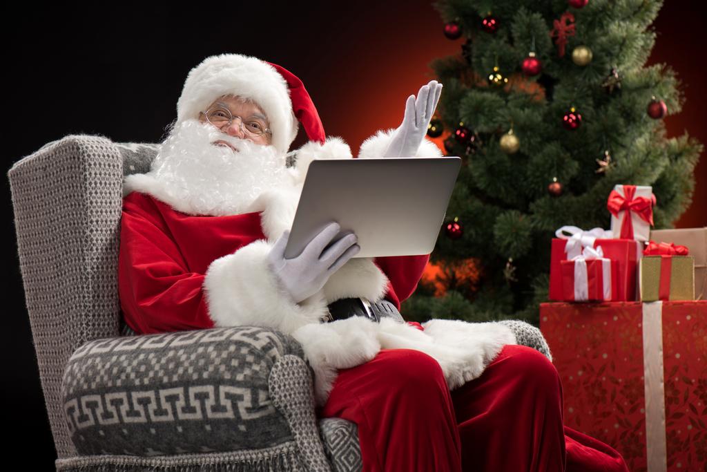 Papai Noel usando laptop e gestos
 - Foto, Imagem
