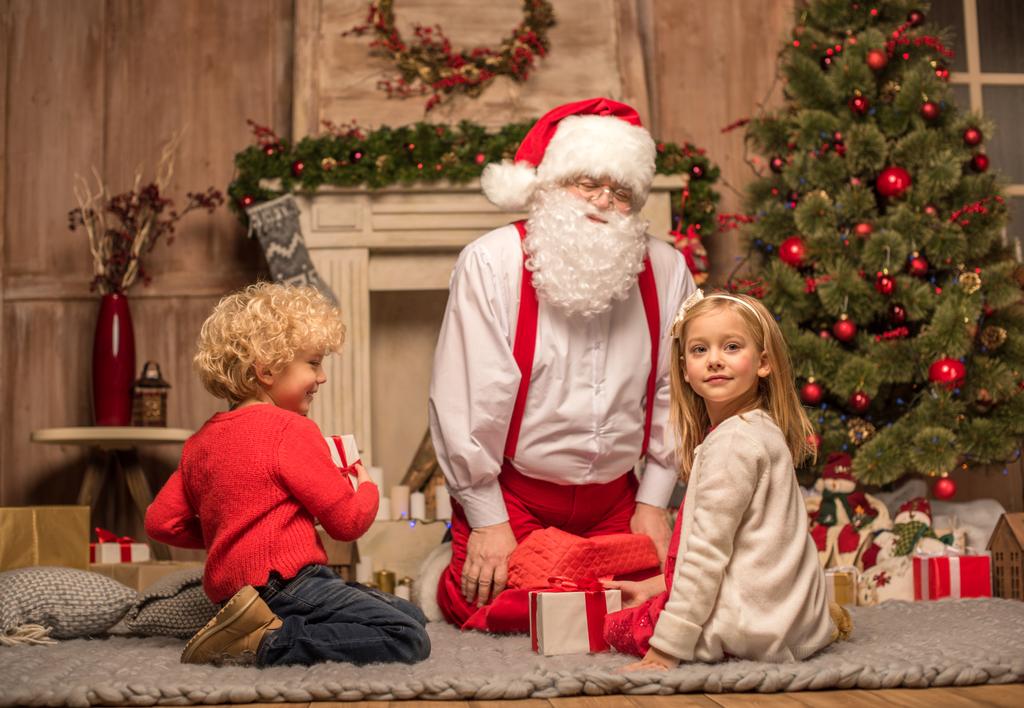 Weihnachtsmann und Kinder mit Weihnachtsgeschenken - Foto, Bild