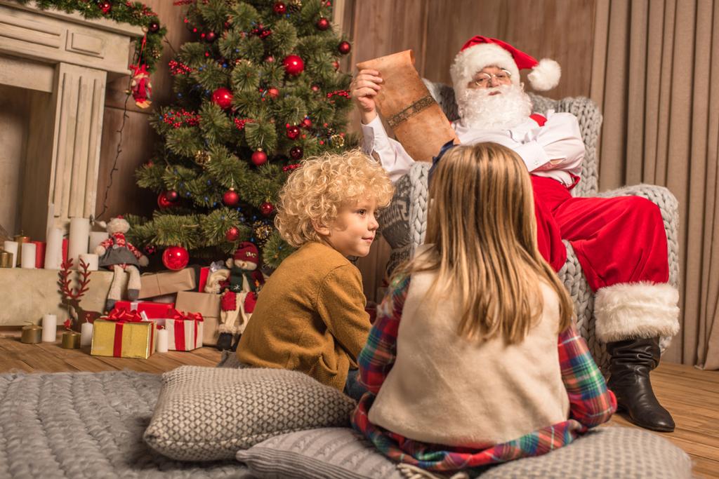 Santa Claus con niños leyendo la lista de deseos
  - Foto, imagen
