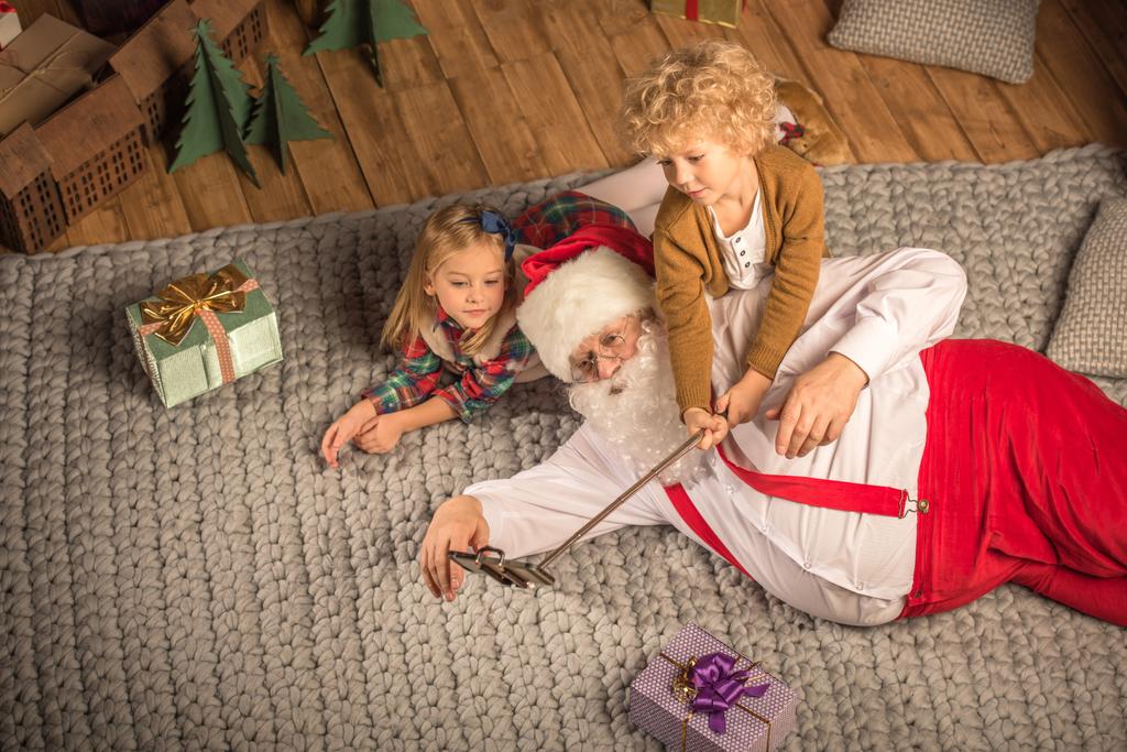 Joulupukki lasten kanssa ottaen selfie
  - Valokuva, kuva