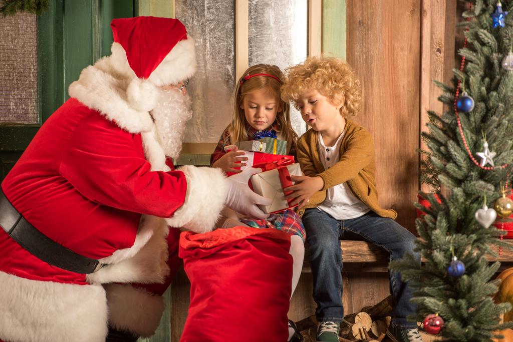 Papai Noel dando caixas de presente para crianças
  - Foto, Imagem