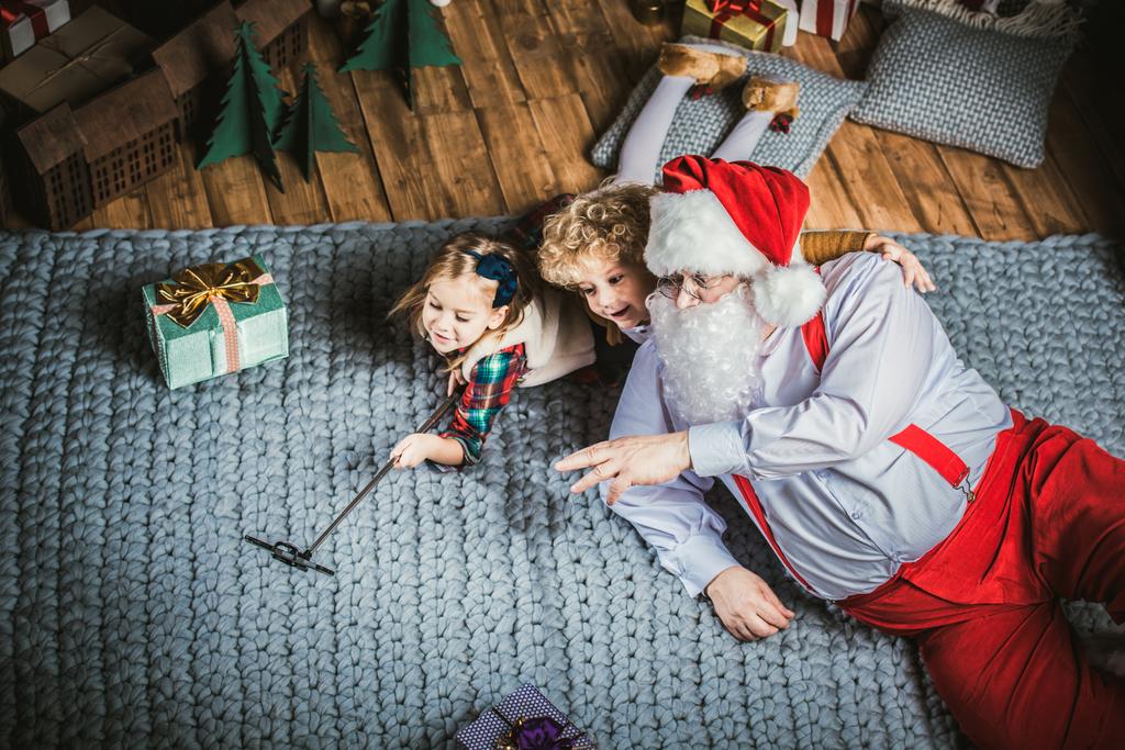 Санта-Клаус с детьми, делающими селфи
  - Фото, изображение