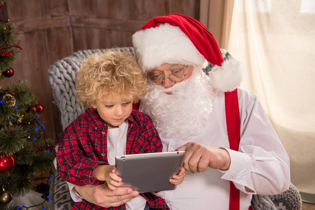 Άγιος Βασίλης με κατσίκι στο γόνατο χρησιμοποιώντας tablet - Φωτογραφία, εικόνα