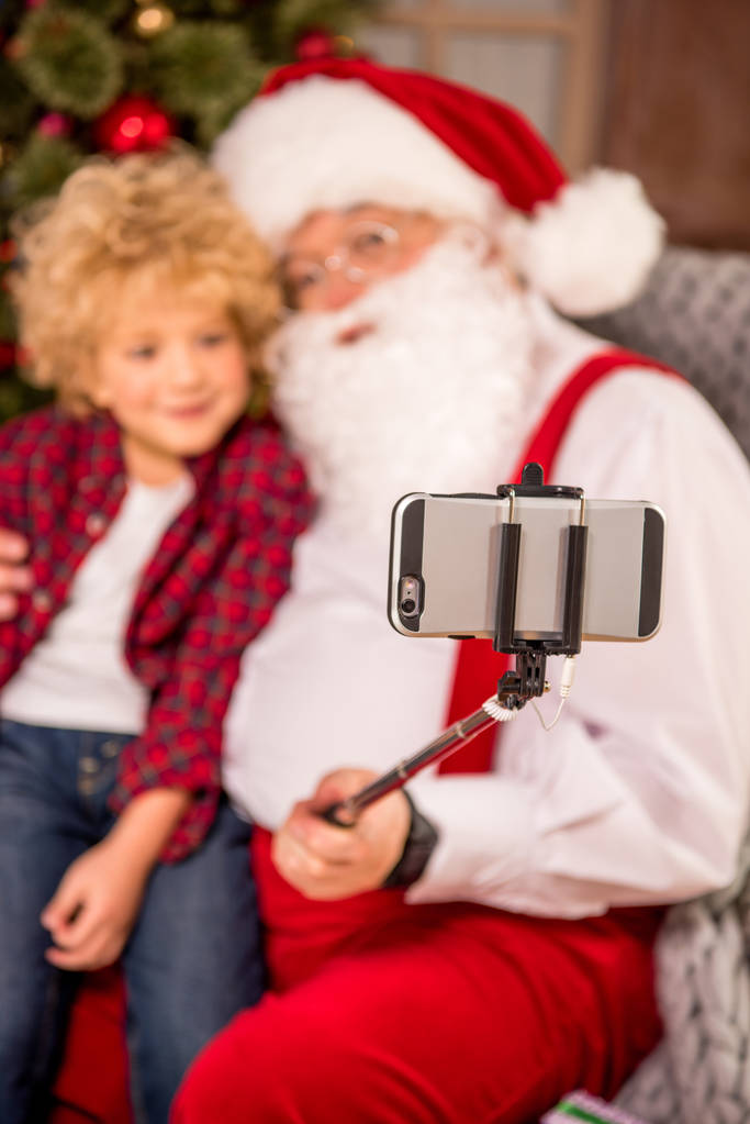 Papá Noel con niño en la rodilla
 - Foto, Imagen