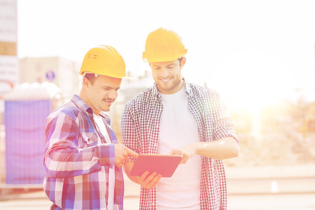 Lächelnde Bauarbeiter in Harthüten mit Tablet-PC - Foto, Bild