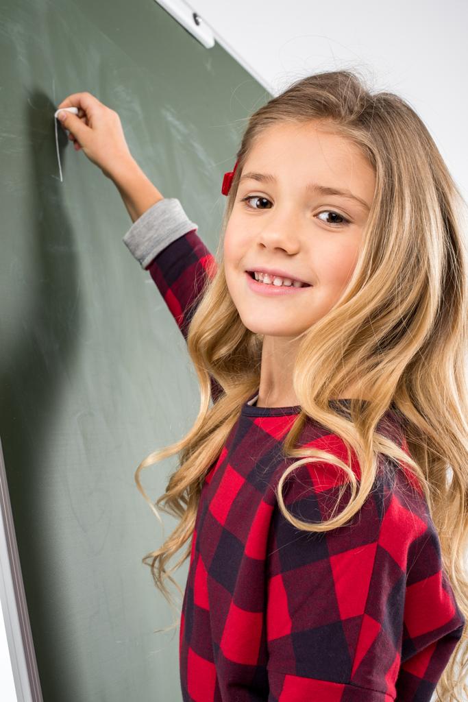 Schoolgirl writing on blackboard - Photo, Image