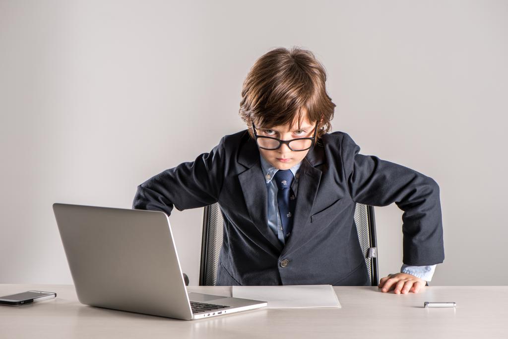 Bambino in giacca e cravatta in piedi sopra la scrivania
 - Foto, immagini