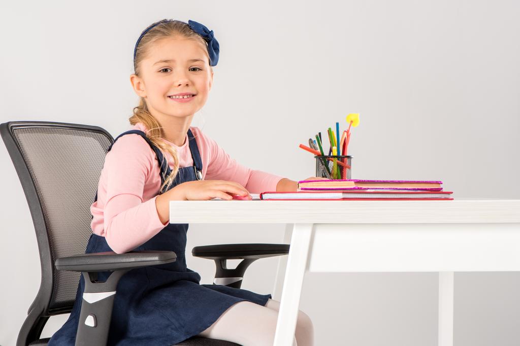 Écolière souriante assise au bureau avec des livres
 - Photo, image
