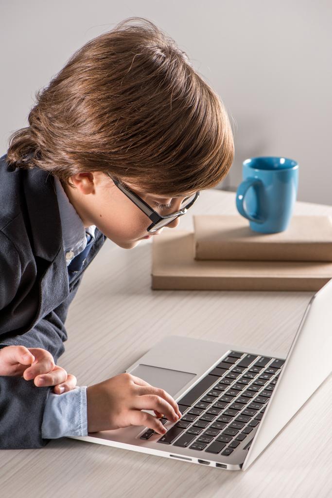 Schoolchild in business suit using laptop computer - Photo, Image