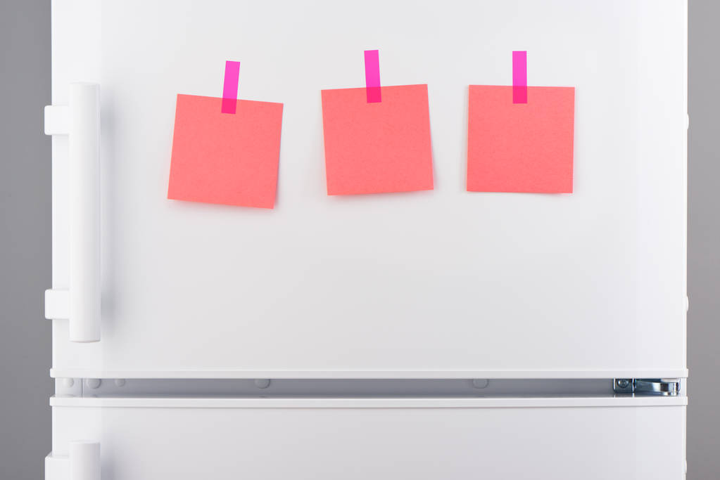Notes en papier rose attachées avec des autocollants sur réfrigérateur blanc
  - Photo, image