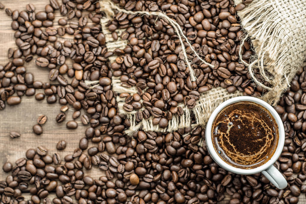 豆の焙煎の背景にオーバーヘッドのブラック コーヒー カップ - 写真・画像