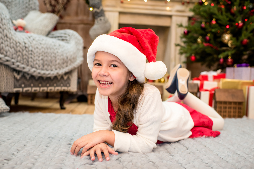 Kind mit Weihnachtsmütze auf Teppich liegend  - Foto, Bild
