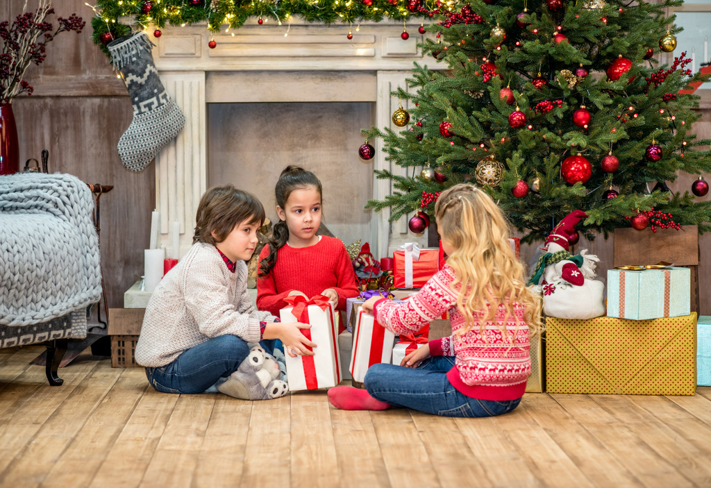 τα παιδιά που κάθονται στο πάτωμα με τα δώρα Χριστουγέννων - Φωτογραφία, εικόνα