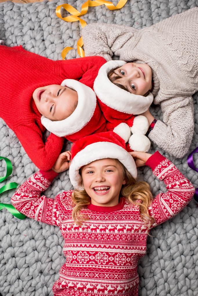 bambini in cappelli Babbo Natale sdraiati in cerchio
 - Foto, immagini