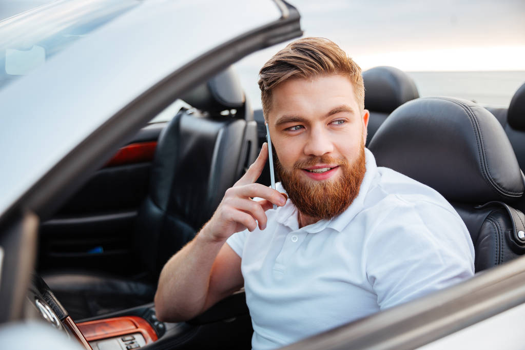 Νεαρός μιλώντας στο τηλέφωνό του και την οδήγηση ενός αυτοκινήτου - Φωτογραφία, εικόνα