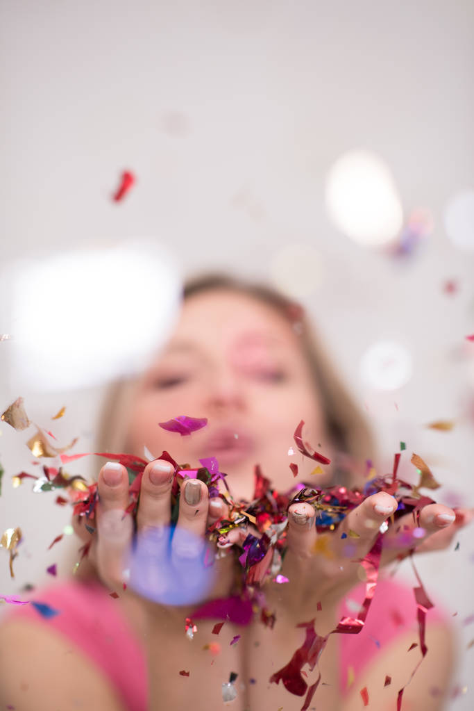 Beautiful  woman blowing confetti in the air party new years eve celebration isolated on white background - Photo, Image