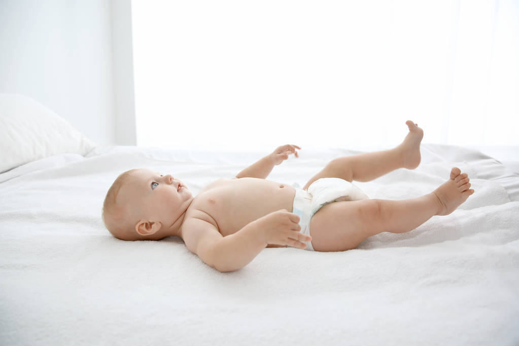 Little baby on white bed in room - Photo, Image