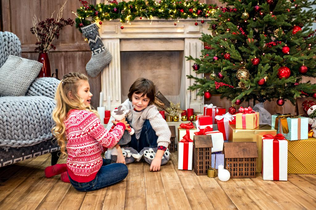 Niños sentados cerca de cajas de regalo
   - Foto, imagen