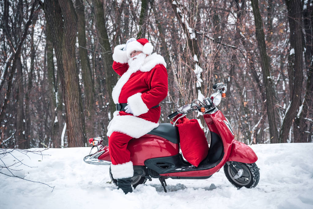 Joulupukki istuu punaisella skootterilla
 - Valokuva, kuva