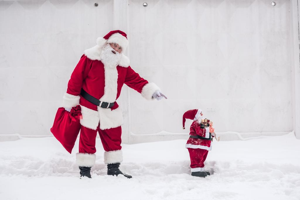 Weihnachtsmann zeigt auf Weihnachtsspielzeug  - Foto, Bild
