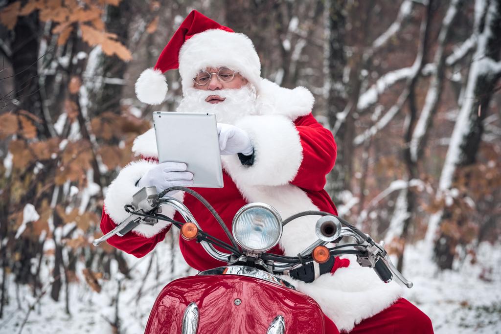 Santa Claus on scooter using tablet  - Photo, Image
