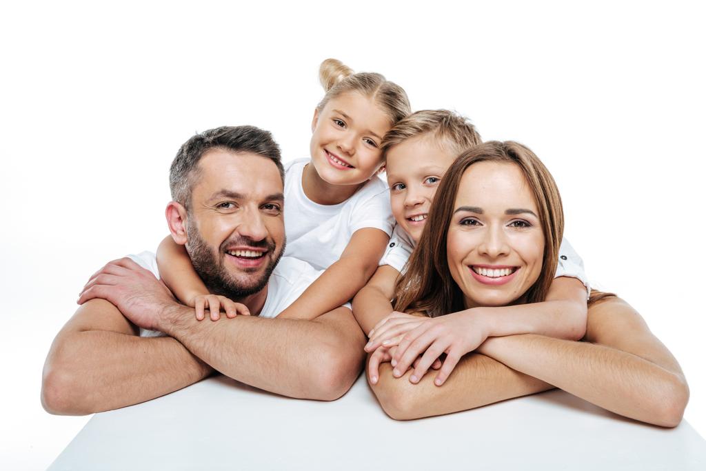 Χαμογελώντας οικογένεια σε λευκά μπλουζάκια αγκάλιασμα  - Φωτογραφία, εικόνα