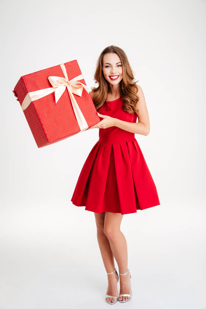 Gelukkige vrouw in rode jurk bedrijf geschenkdoos - Foto, afbeelding