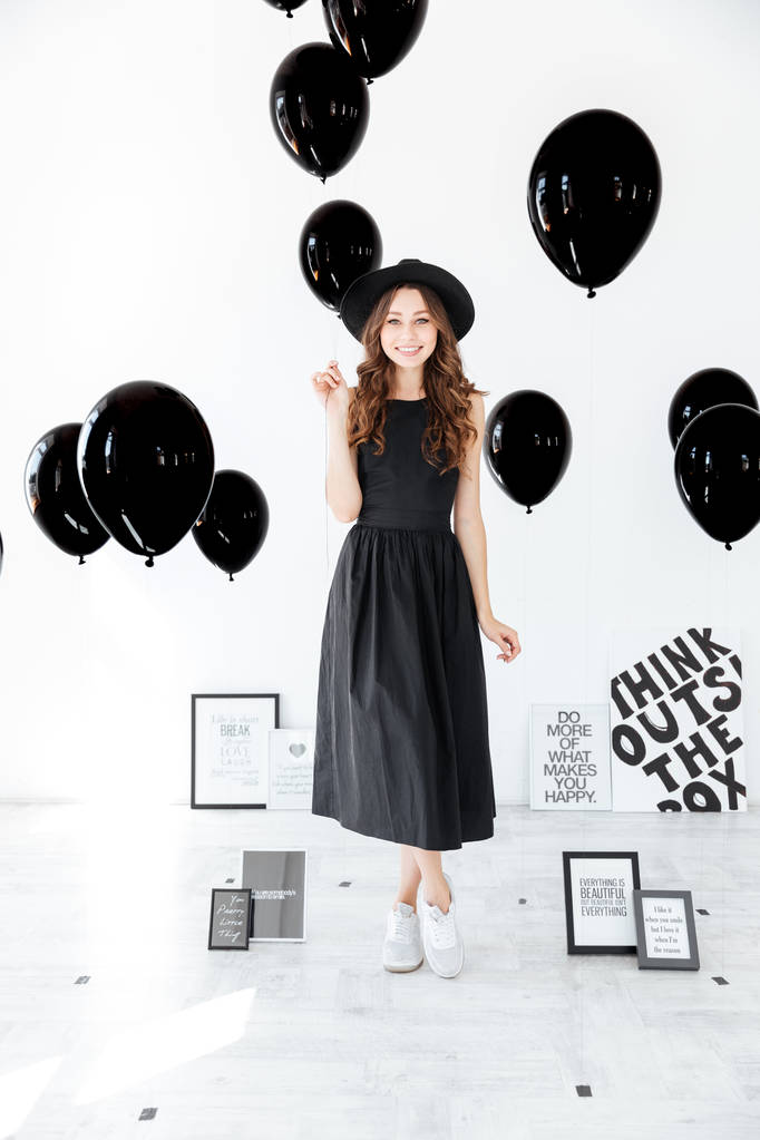 Повна довжина весела жінка стоїть і тримає чорні кульки
 - Фото, зображення