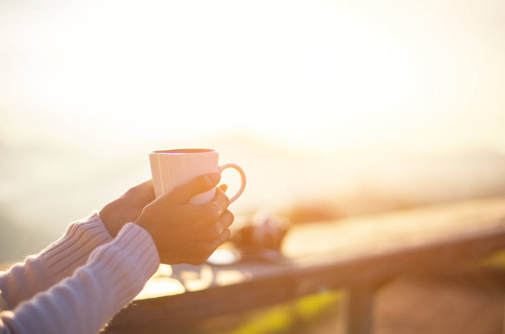 Donna che beve caffè al sole seduta all'aperto sotto la luce del sole godendo il suo caffè del mattino, vintage, soft e select focus
 - Foto, immagini