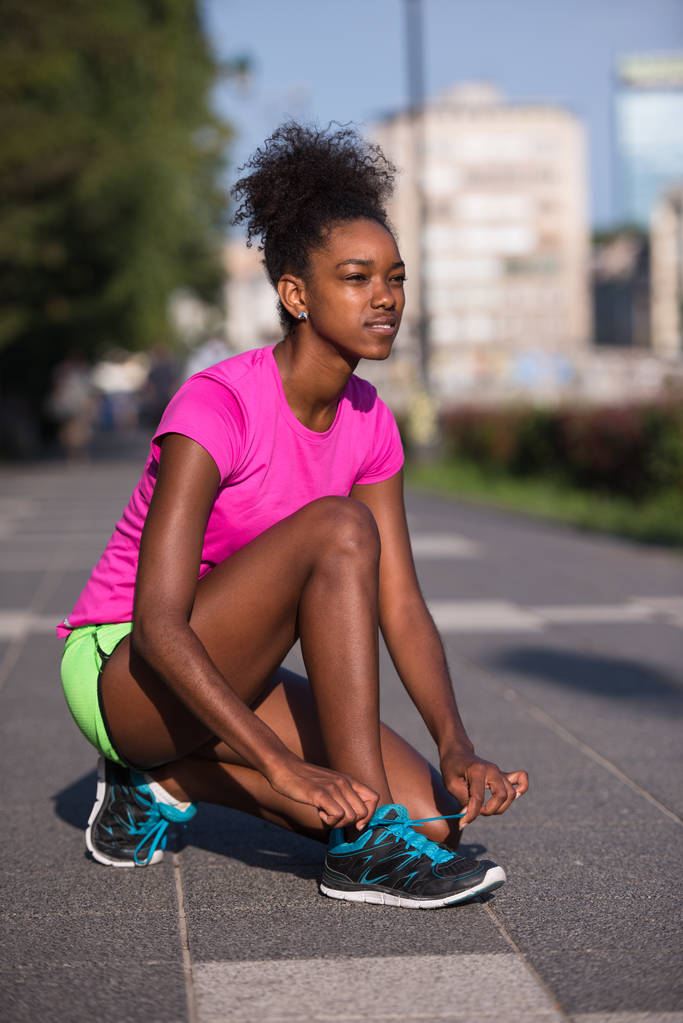 アフリカ系アメリカ人の女性ランナーの靴ひもを締め - 写真・画像