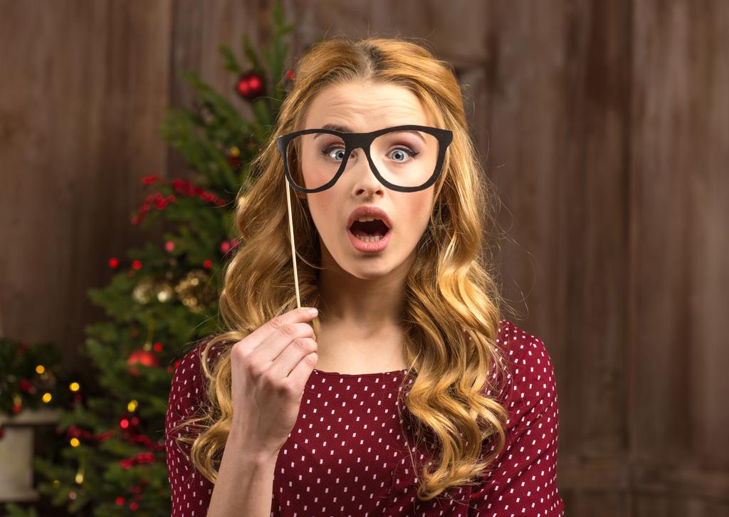 Mulher surpresa segurando óculos de festa
 - Foto, Imagem