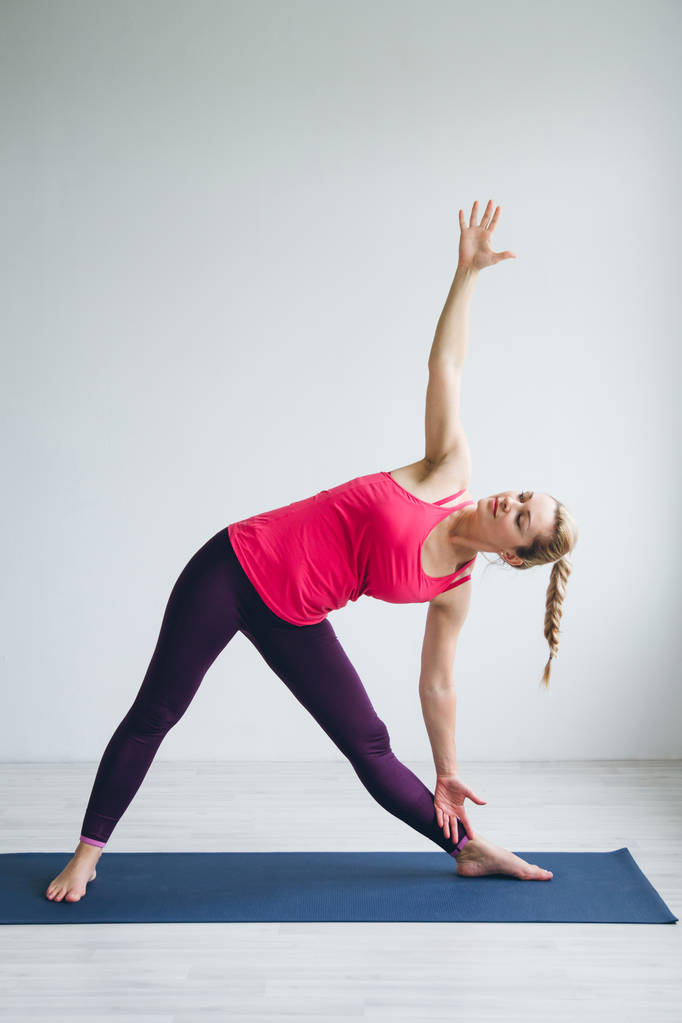Beyaz yoga egzersizleri yapıyor bir odada genç kadın . - Fotoğraf, Görsel