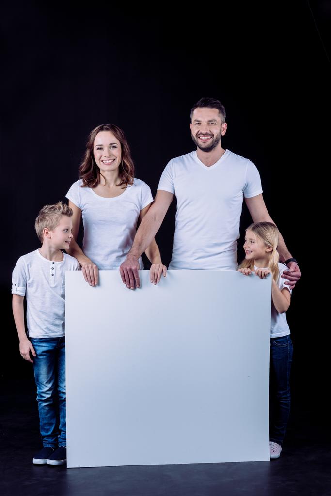 Famille souriante tenant une carte blanche
 - Photo, image
