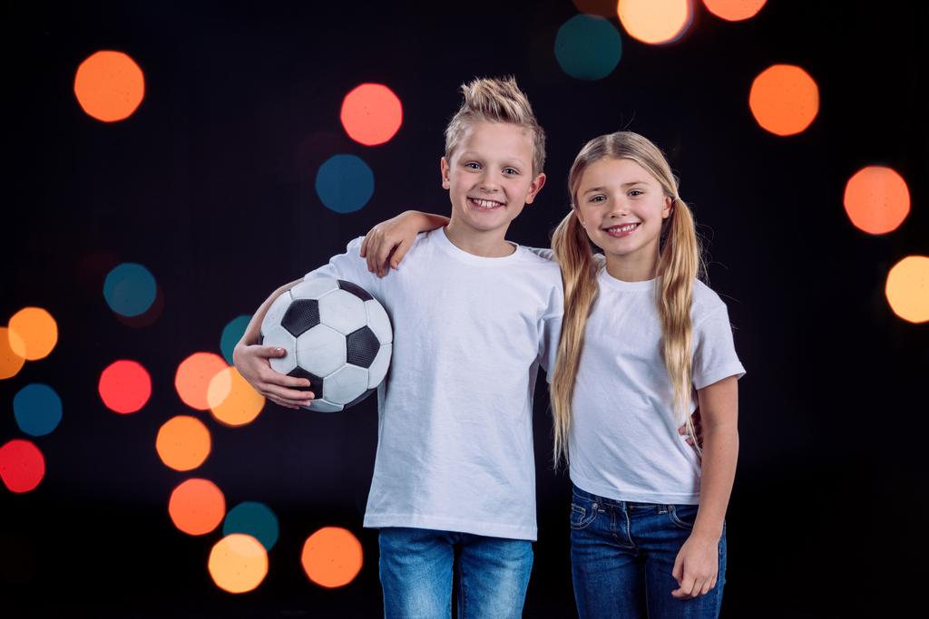 hermano y hermana posando con pelota de fútbol
 - Foto, Imagen