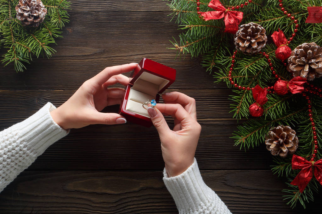 木材の背景のクリスマスの装飾の中で女性の手で婚約指輪 - 写真・画像